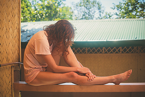 A young woman is relaxing on a porch in the tropics