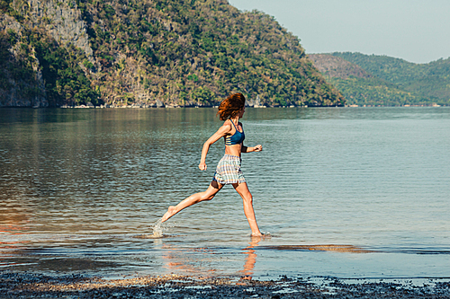 A young woman is runing on a tropical beach