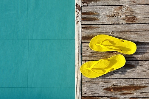 Yellow sandals by a swimming pool