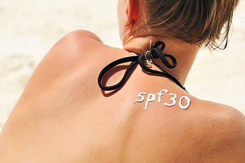 Sunscreen lotion over tan woman skin made as SPF 30 word