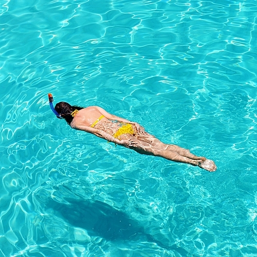 Woman snorkeling in crystal clear turquoise water at tropical beach