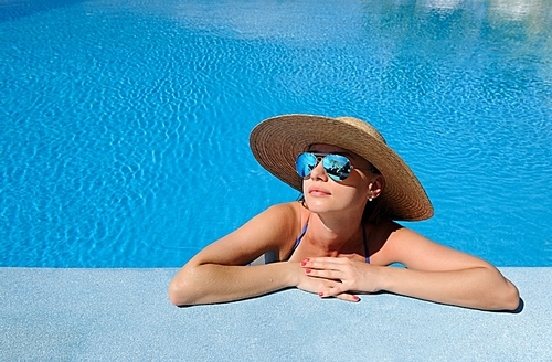 Woman in hat relaxing at the pool