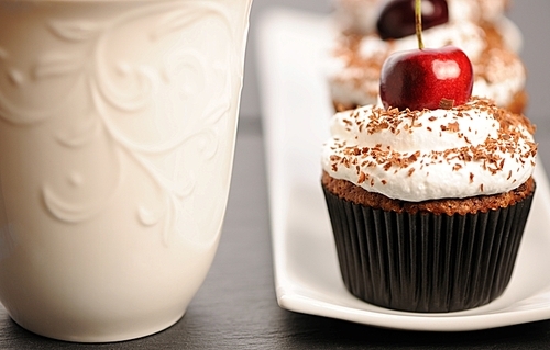 Cupcakes with whipped cream and cherry on a table