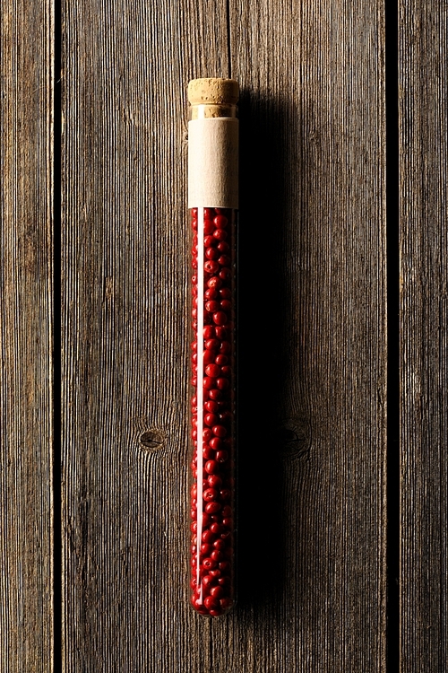 Rose pepper in beaker on wooden background