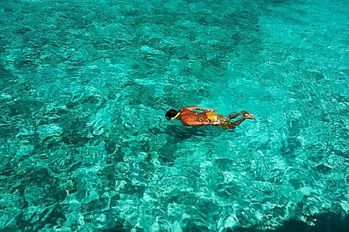 Man snorkeling in crystal clear turquoise water at tropical beach