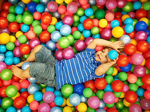 Happy child playing at colorful plastic balls playground high view