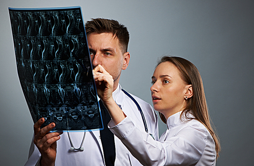 Medical doctors team with MRI spinal scan portrait against grey background
