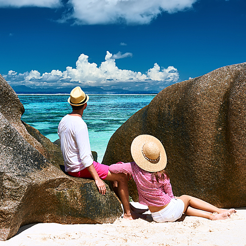 Couple relaxing among granite rocks on a tropical beach Anse Source d’Argent at Seychelles|La Digue.