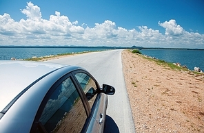 Car driving across ocean by the road