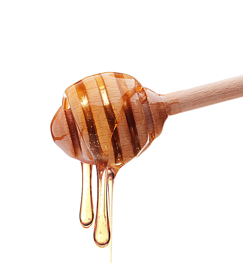 Honey dripping from a wooden honey dipper isolated on white cutout