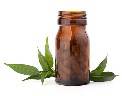 Herbal drug capsules in brown glass bottle isolated on white cutout. Alternative medicine concept.