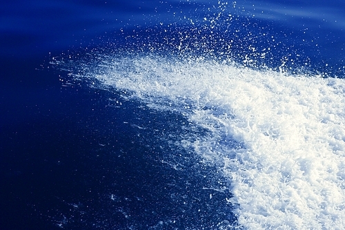 Water splash at the starboard boat side on blue ocean sea