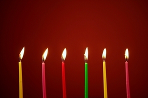 Colorful birthday light candles in a row red background