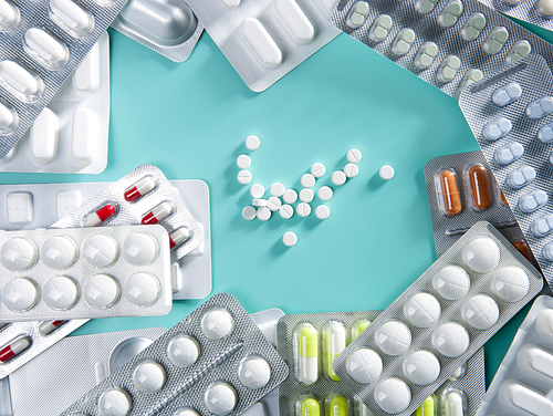 blisters of medical pills over greenbackground as a pharmaceutical industry concept