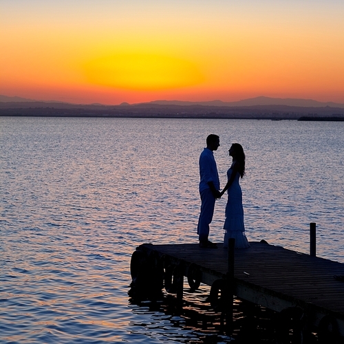 couple in love back light silhouette at lake sunset full length