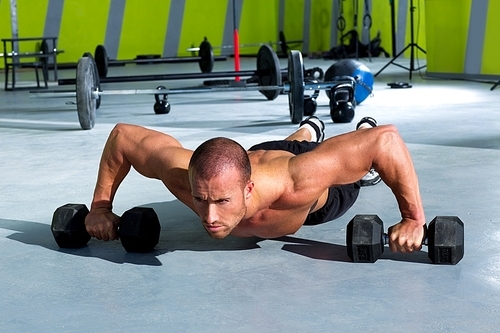 Gym man push-up strength pushup exercise with dumbbell in a crossfit workout