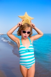 child kid girl in summer beach vacations with starfish and aqua sea
