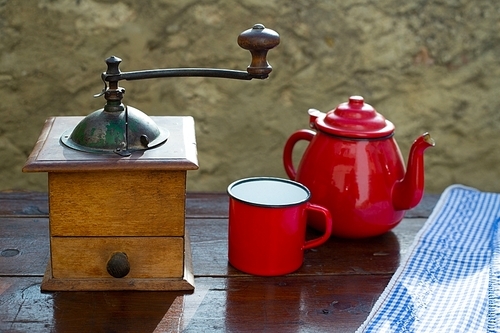 retro old coffee grinder with vintage teapot and red cup