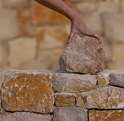 Mason hands working on masonry stone wall stonewall