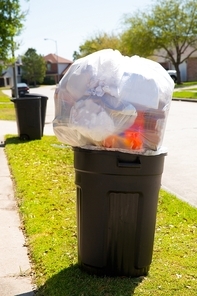 Trash bin dustbin full of excess garbage on street lawn