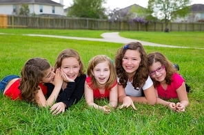 Children girls group lying on lawn grass smiling happy together in a row