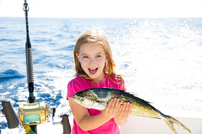 Blond kid girl fishing Dorado Mahi-mahi fish happy with trolling catch on boat deck