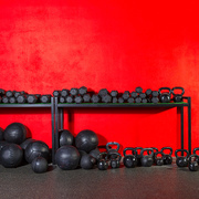 Kettlebells dumbbells and weighted slam balls weight training equipment at gym red wall