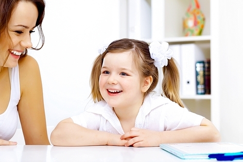 Young mother and her little girl studying together at home