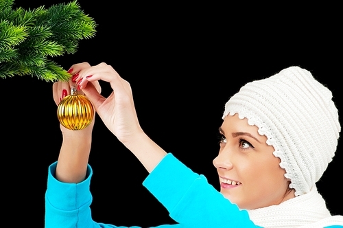 Young girl decorating christmas tree isolated on black