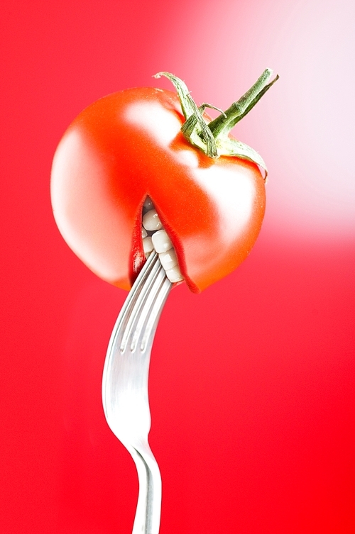 Red tomato with mouth on red background