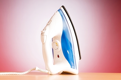 Modern electric iron against the colorful background