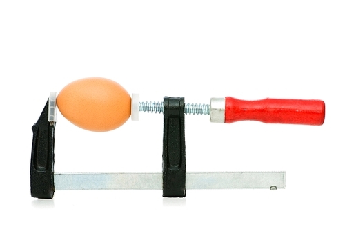 Strength concept with egg and clamp on white