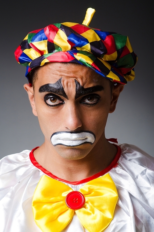 Sad clown against dark background