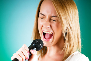 Girl singing with microphone against gradient background