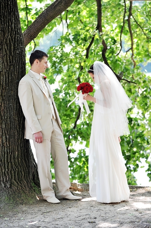 groom and bride in white dress on background of green trees