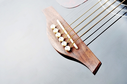 Detail of an acoustic black guitar with the strings