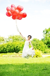 bride in  white dress with balloons  on  green field