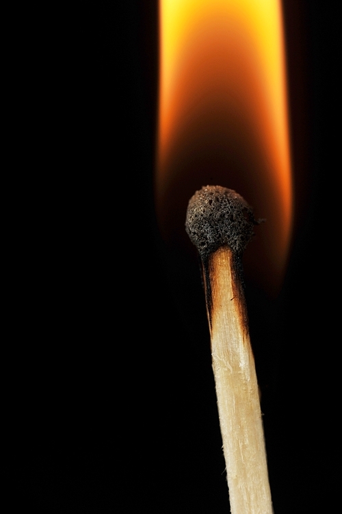 ignited matchstick flame in dark close up