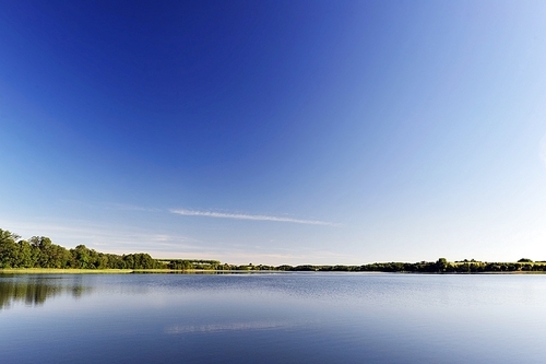 calm water of  lake|woods on other side and  blue sky. landscape