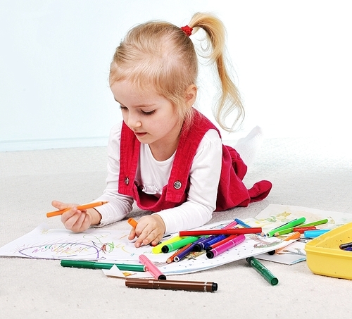 Beautiful little girl is drawing  on paper