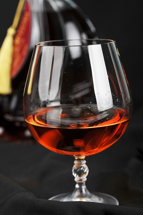Simple composition of glass and bottle cognac. black background