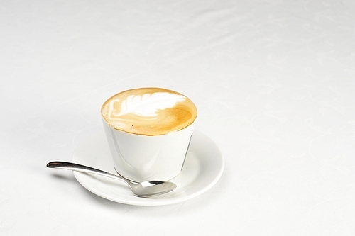 White cup of cappuccino with brown and white foam on top. Object  on white