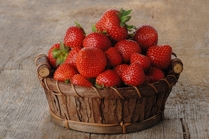Basket of fresh strawberries on wooden board