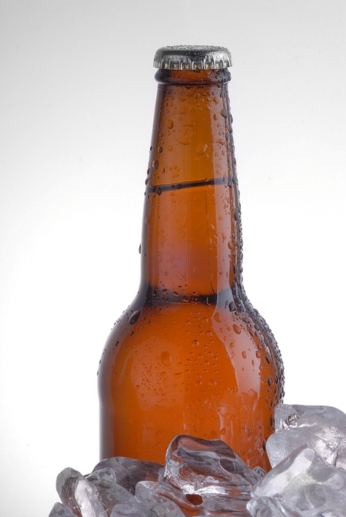brown bottle of beer chilling on ice