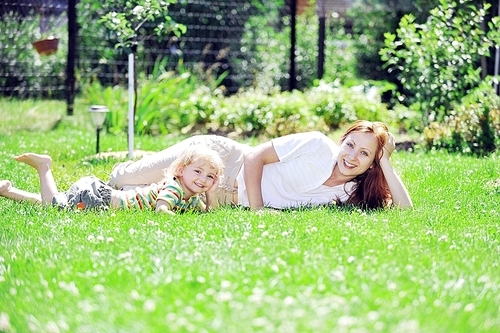 Beautiful young mother with her  daughter playing on grass . summer.