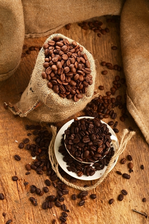 유토이미지 | Roasted coffee beans in jute sack and cup on wooden background