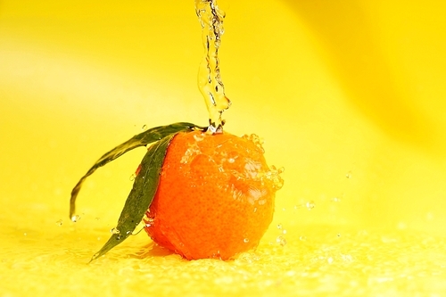 tangerine and water splashes on yellow|close up