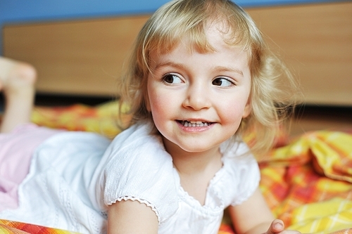 Beautiful little girl lying on bed at house