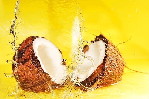 Coconut with  water splash on yellow close up