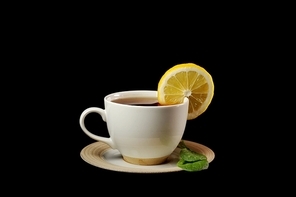 full cup of tea with lemon and  greens  leaves on  black